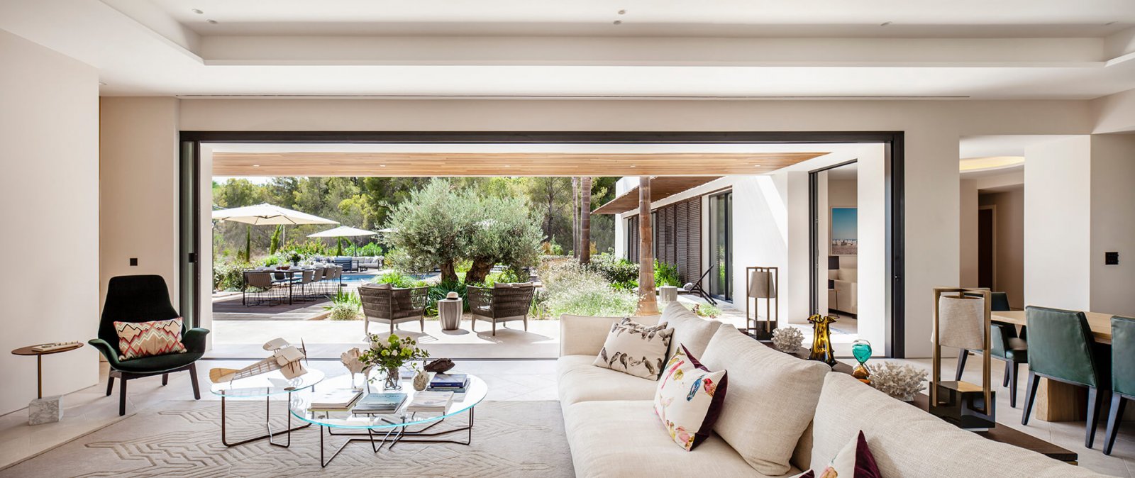 Another view of the living room joined through a large open sliding glass door to the chill-out, garden, and swimming pool, surrounded by trees of the Sol de Mallorca house