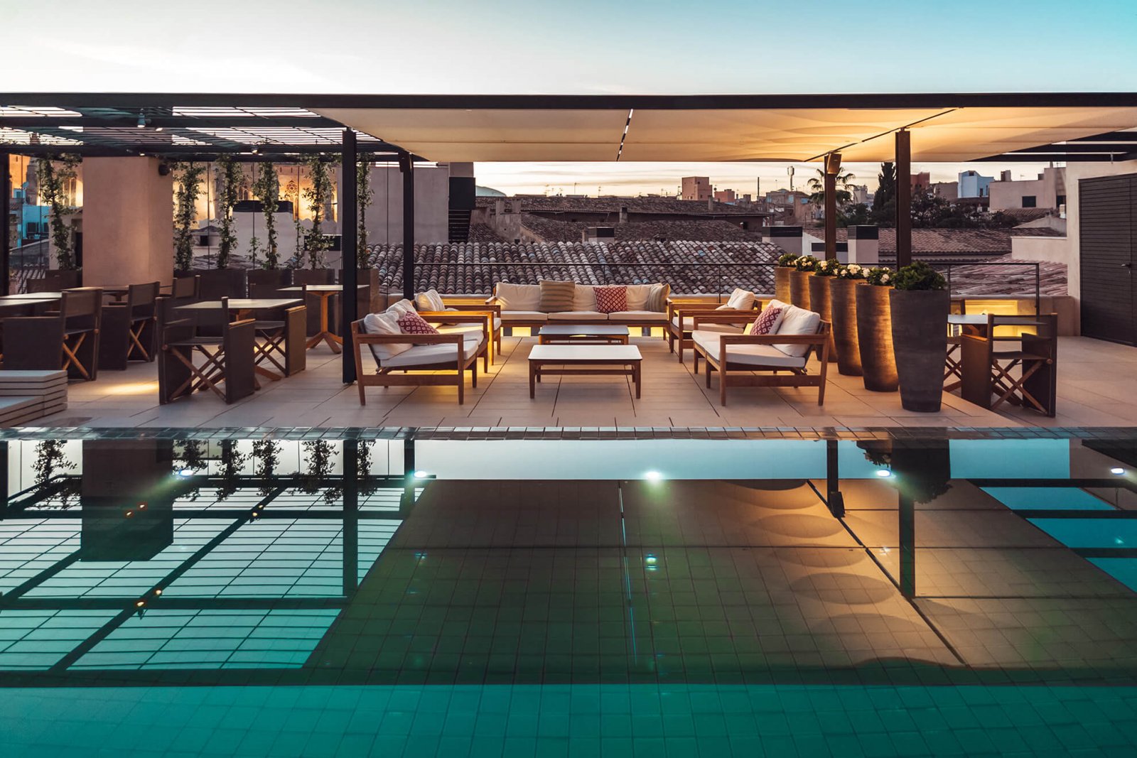 Detail view of the pool and covered chillout area at the Sant Francesc Hotel boutique during sunset with views of the city