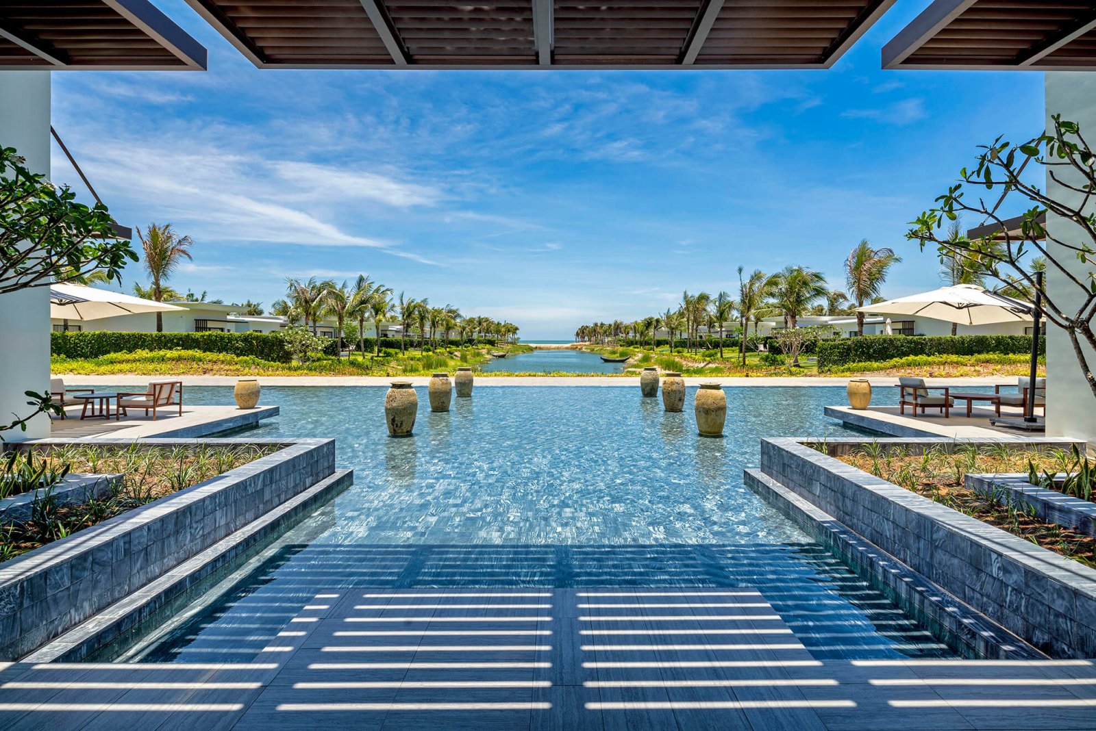 View of the modern swimming pool, with palm trees and the sea in the background