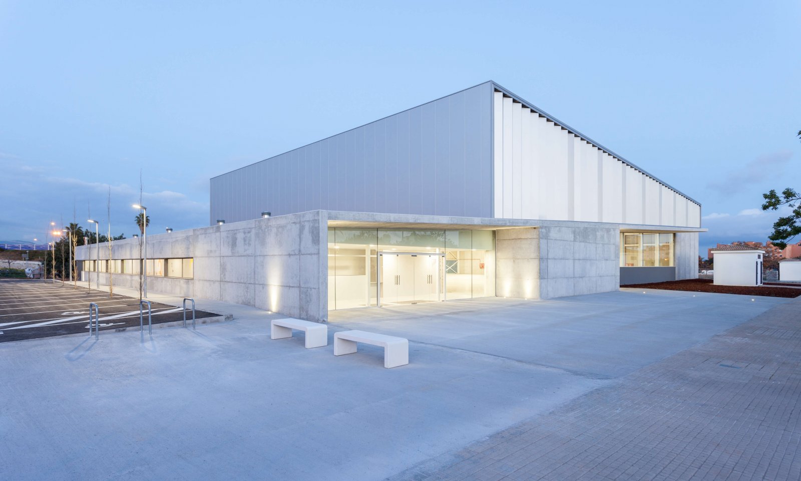 View of the facade of the son ferragut pavilion with asphalt floor and parking on one side