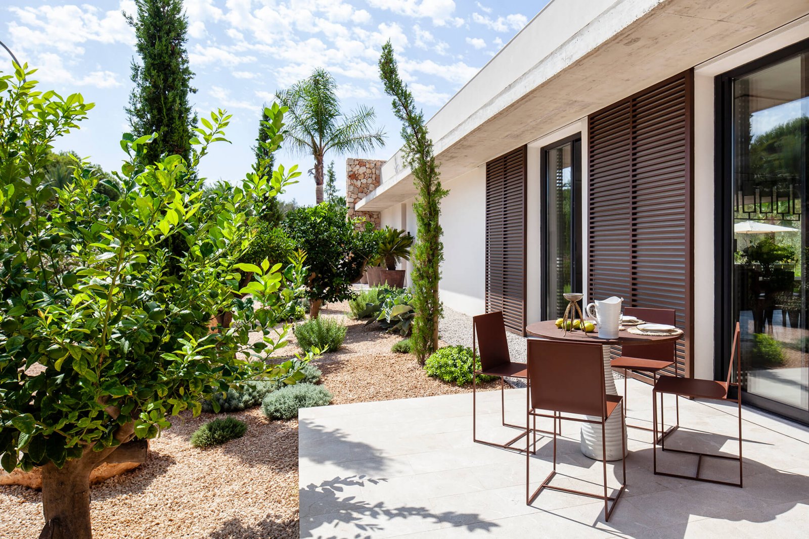 Detail view of the garden with trees, table area and interior facade of the Casa del Sol de Mallorca