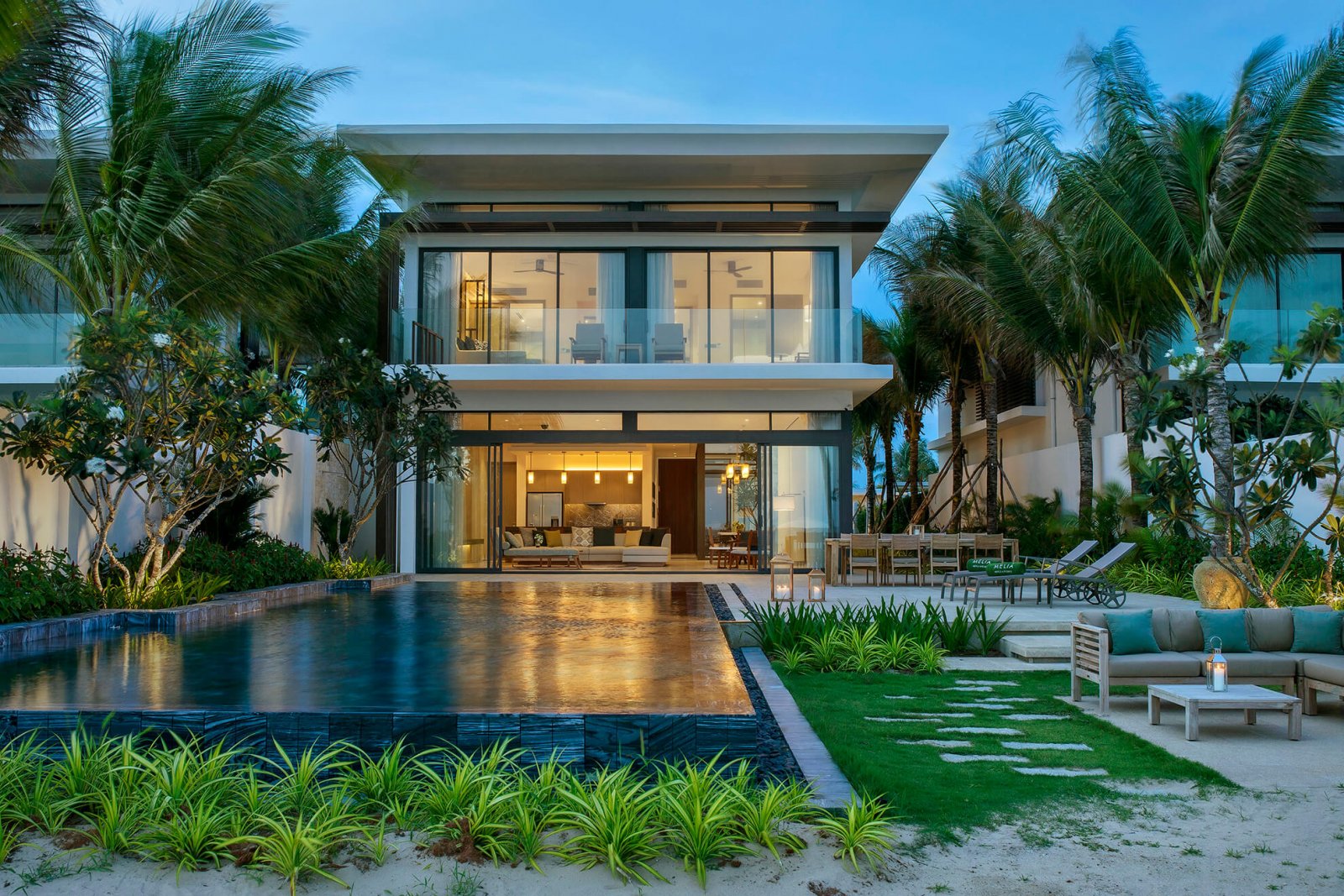 Front view of one of the two plants villas, large windows and pool with garden