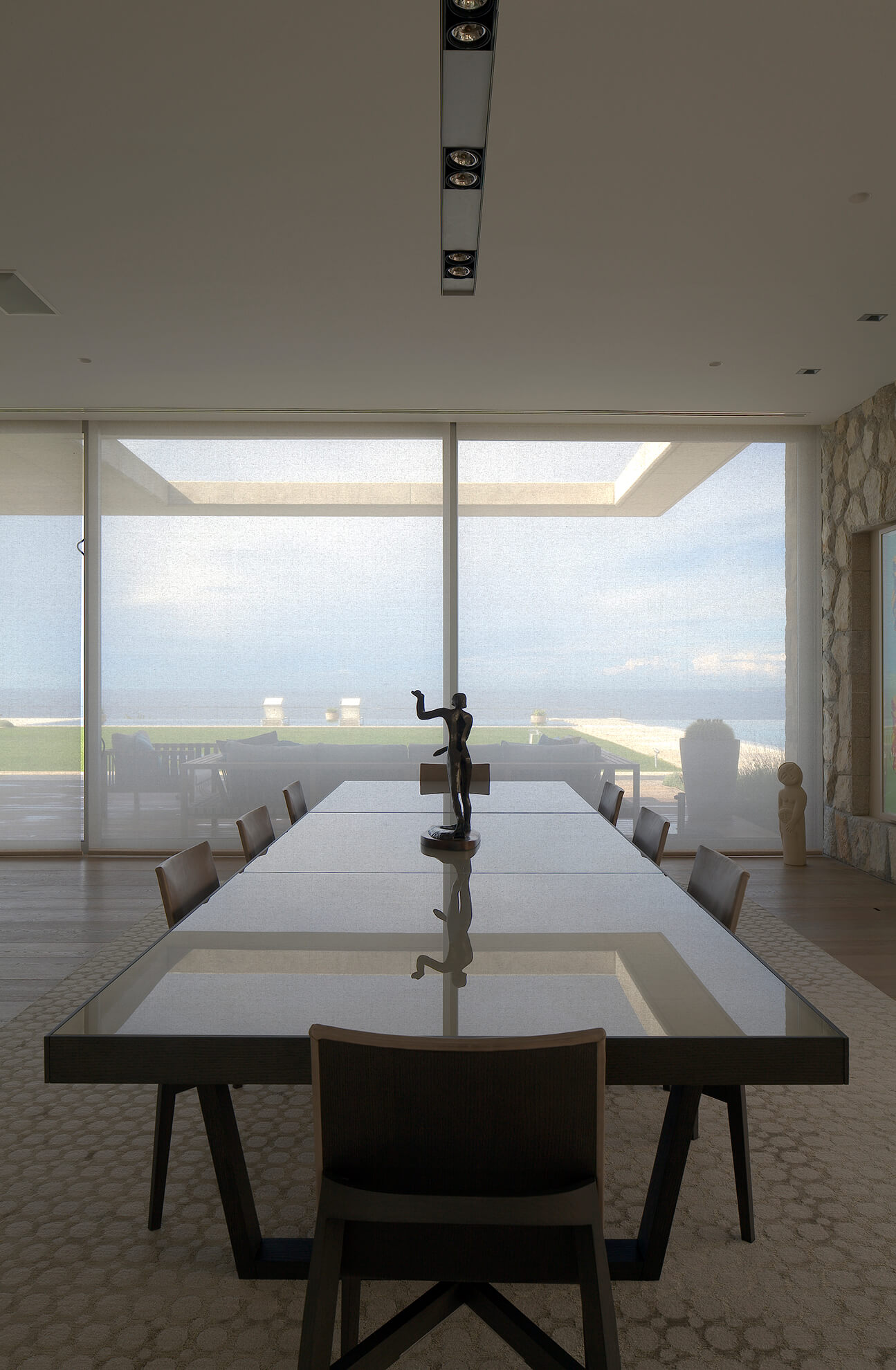 Detail view of the large dining room table, in front of the sliding glass doors that lead to the garden