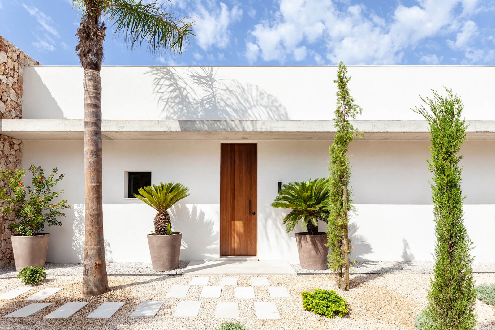 Facade of the inner garden with wooden door and palm trees of the Sol de Mallorca house