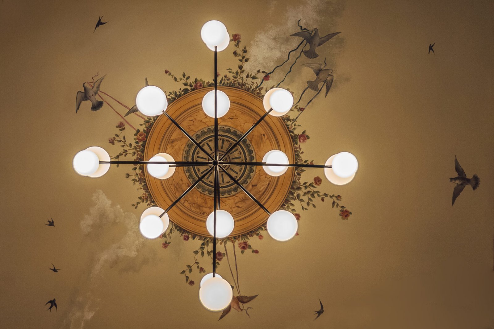 Detail of the ceiling painting with flowers and birds and a modern round bulb lamp