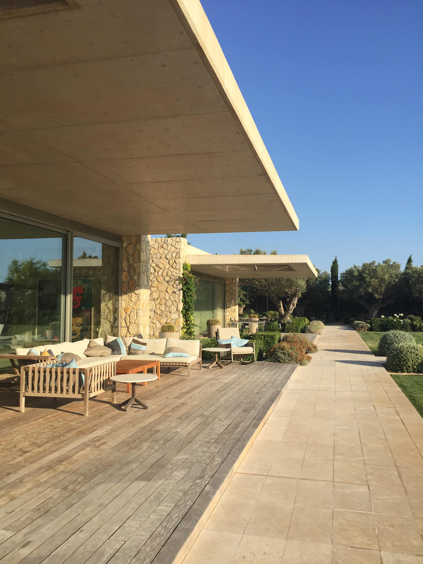 Detail view of one of the chill-out areas covered with outdoor parquet floors, in front of large glass doors and a garden area